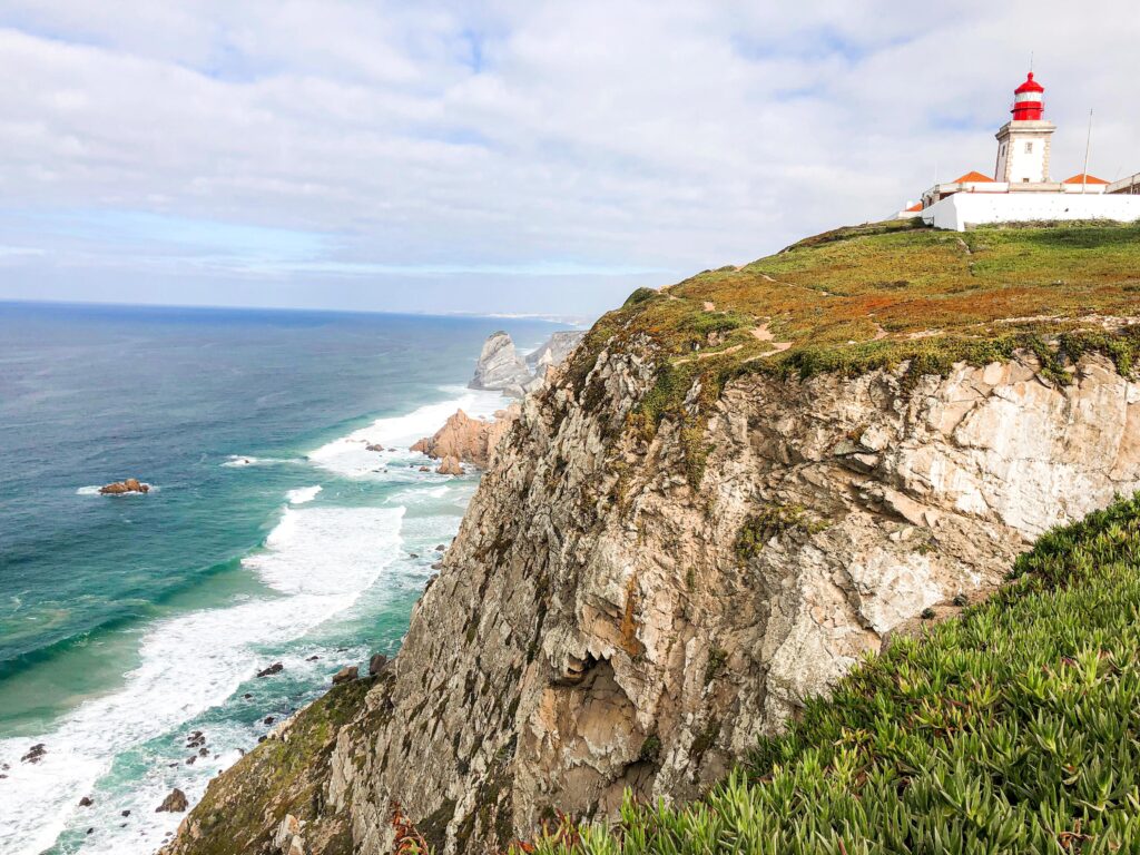 cliff with white lighthouse by the ocean in portugal