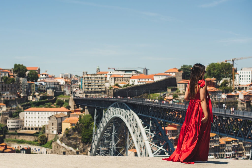 girl in red dress with bridge in background as instagrammable places in porto