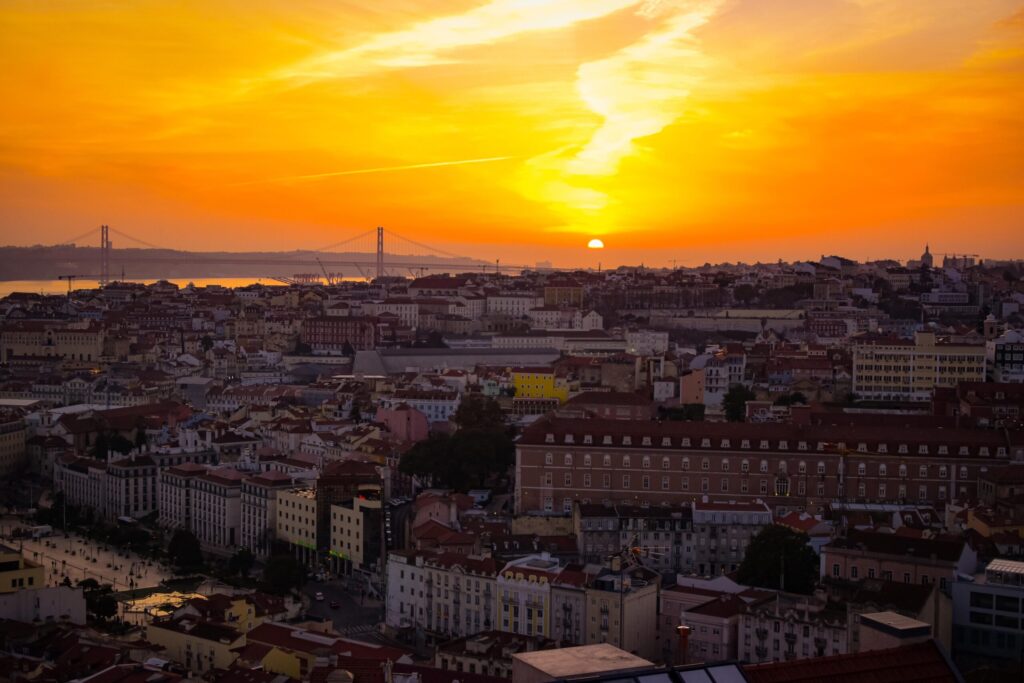 yellow and orange sky at night over city as one of the most instagrammable places in lisbon