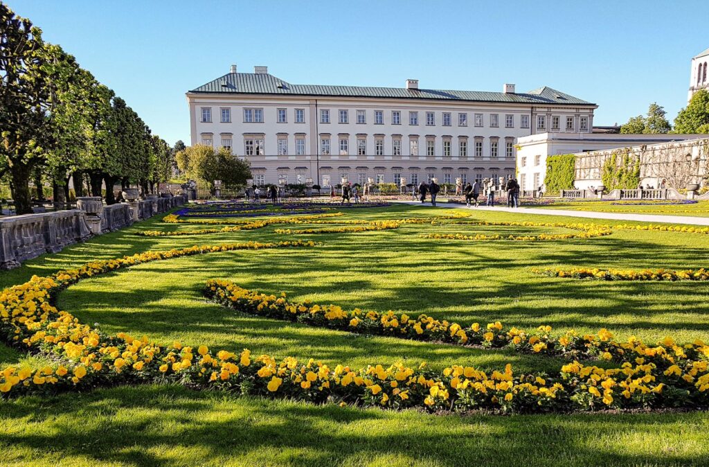 palace with gardens and yellow flowers in front at Mirabell Palace this is a must site to add to any one day Salzburg itinerary