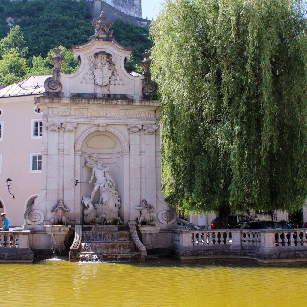 Fountain with green pond and willow tree in one of the beautiful places to see in Salzburg in one day