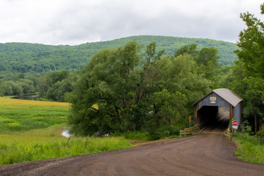 dirt road with covered bridge and grass in a Quebec village 