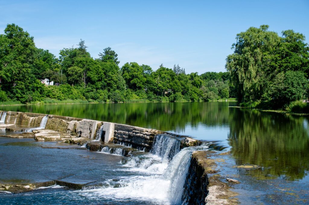 calm water with trees with waterfall in best historic towns in Ontario 
