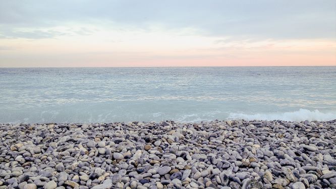 pebble stone beach with sea and pink sunrise in nice france