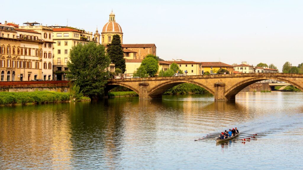 river with rowers and bridge in florence