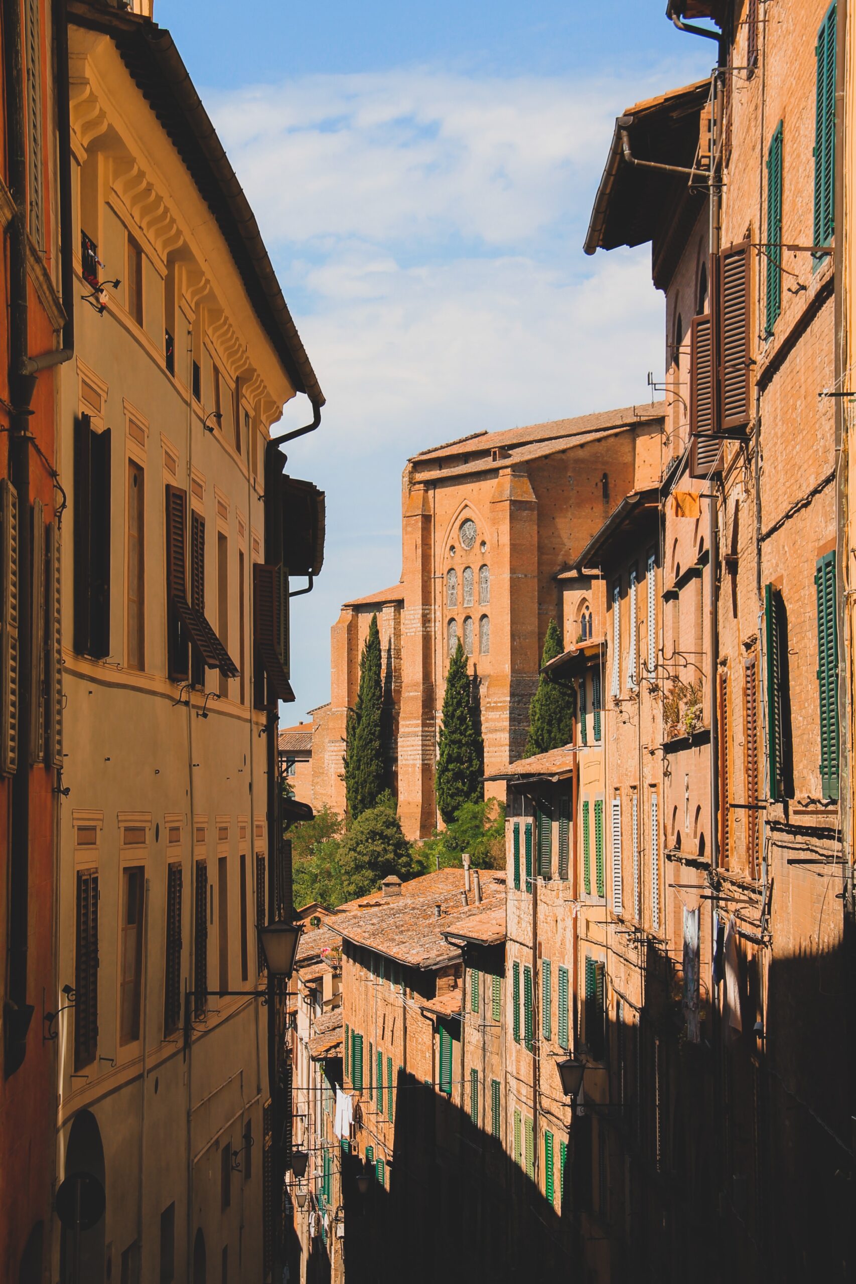 narrow alleyway with view of buildings and church in siena