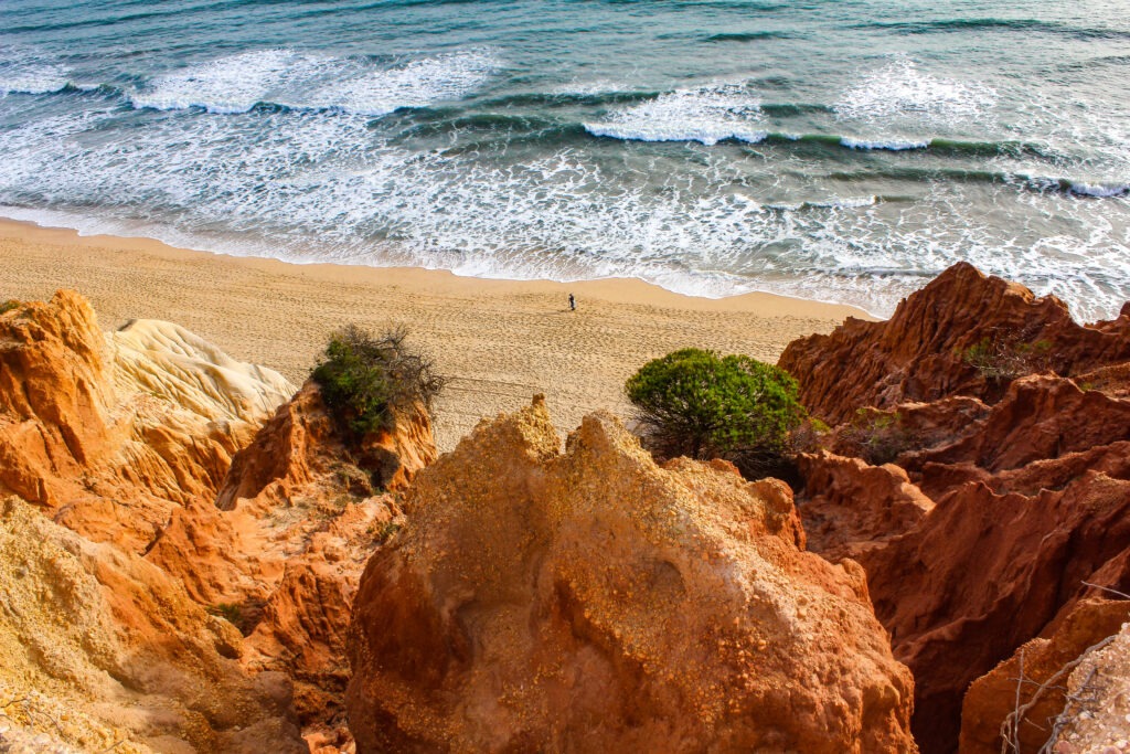 red cliffs with sandy beach and sea with waves in algarve portugal 