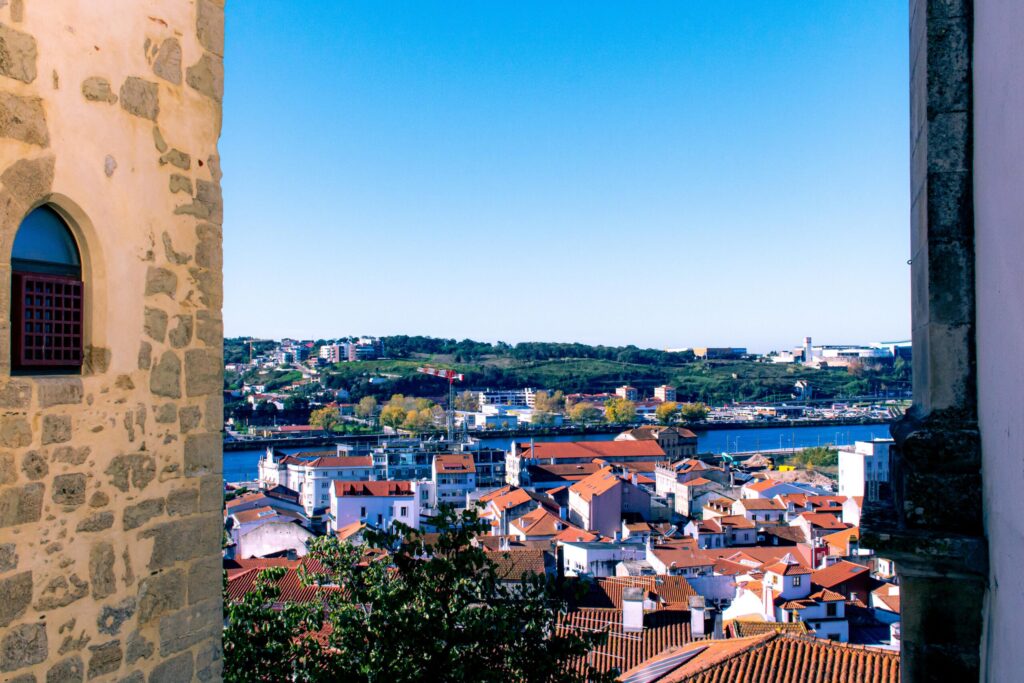 view of city with red roofs and river as coimbra in one day