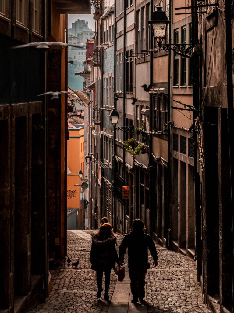 couple walking on narrow street with buildings in porto secret places