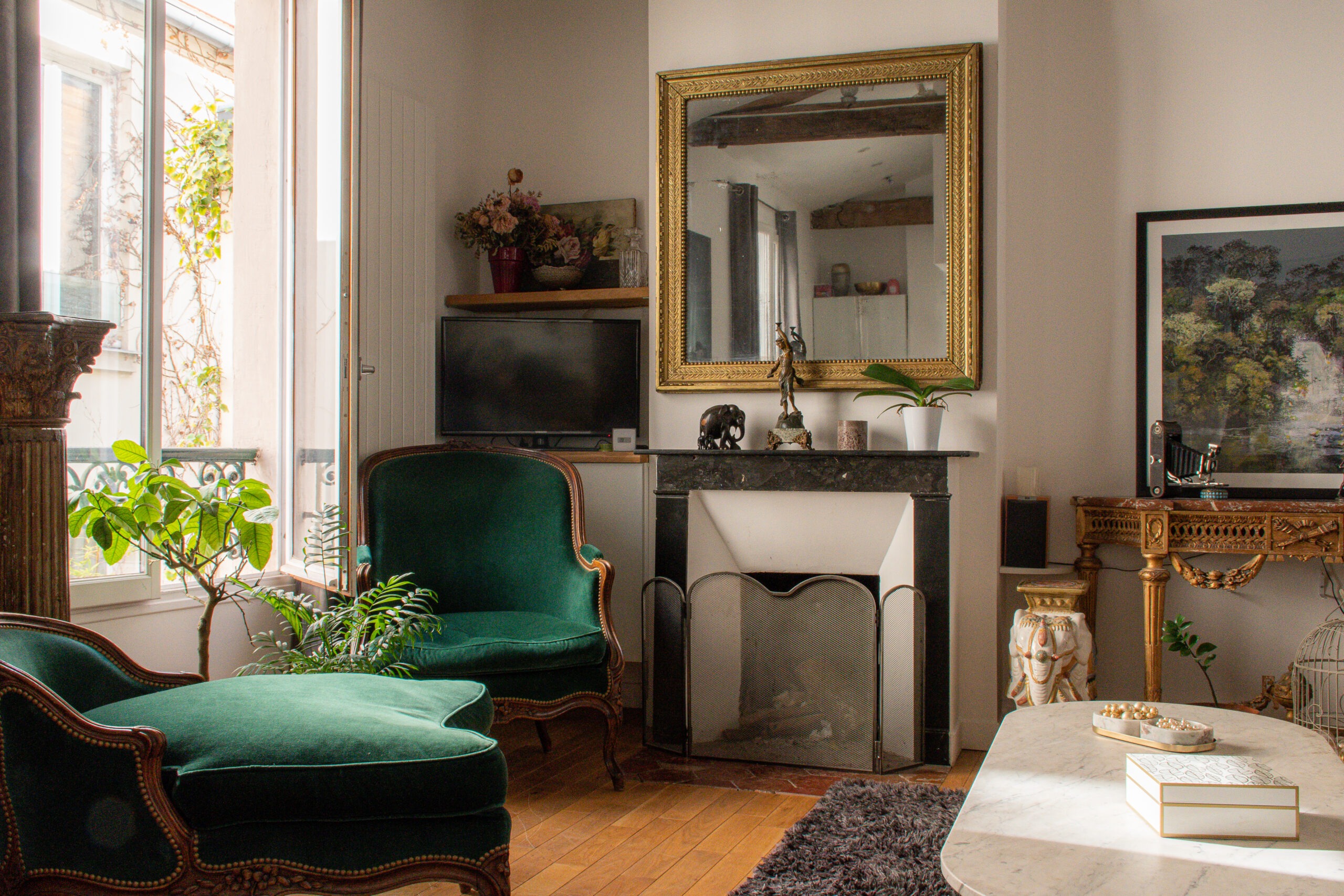 two green velvet chairs by window in Paris apartment in Le Marais