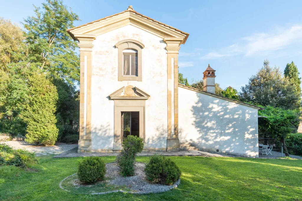 white building with beige stone trim with trees as one of the places to stay in cortona italy