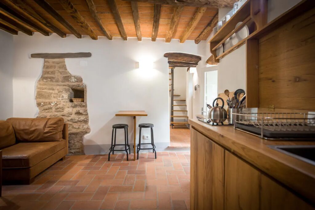 brown leather sofa, beamed ceiling, exposed brick in accommodation in cortona