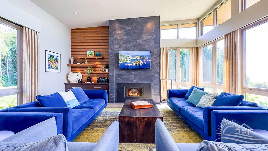 large living space with blue sofa and fireplace with large windows
