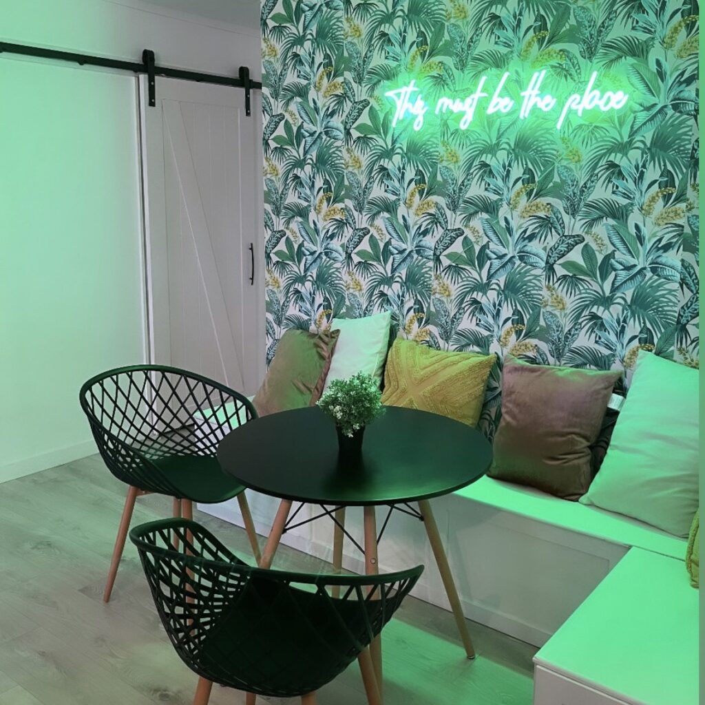 corner banquet with wallpaper and green neon sign in airbnb grand bend