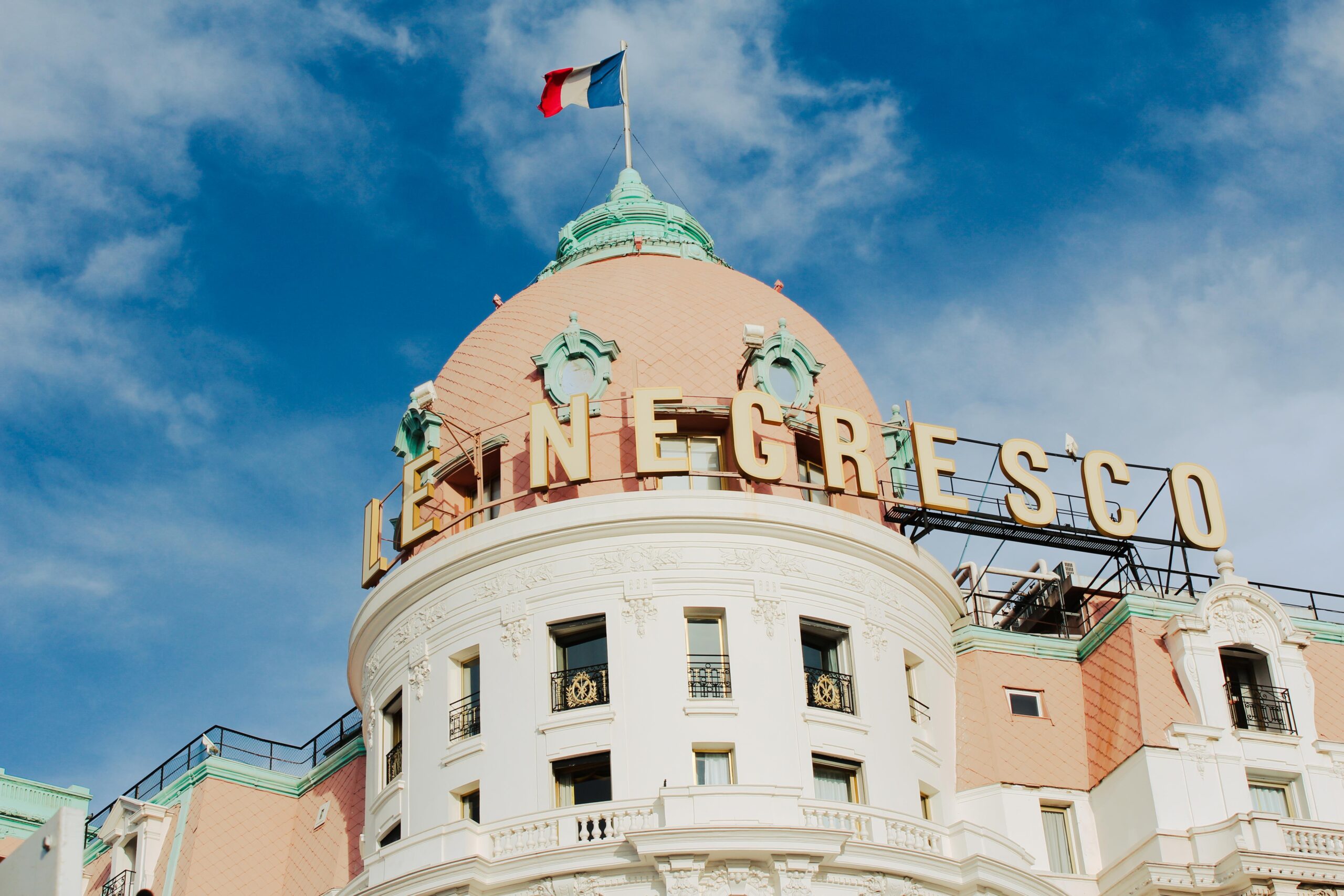 white hotel with pink dome and french flag on hotel negresso in nice france