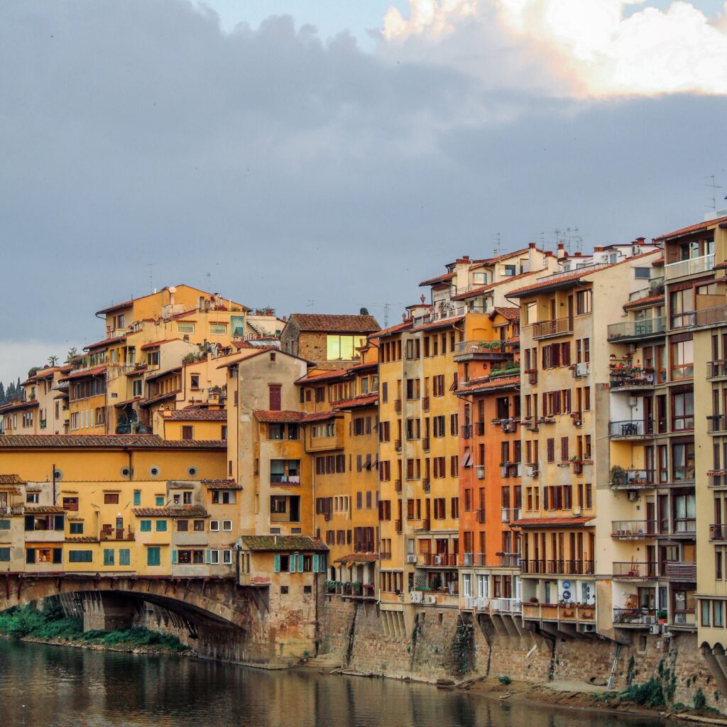 tall buildings in yellows and orange with bridge and river in 24 hours in florence