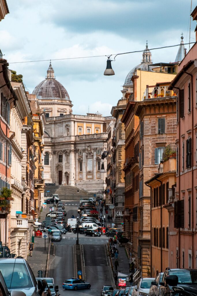 rome street on hill with cars and view of dome