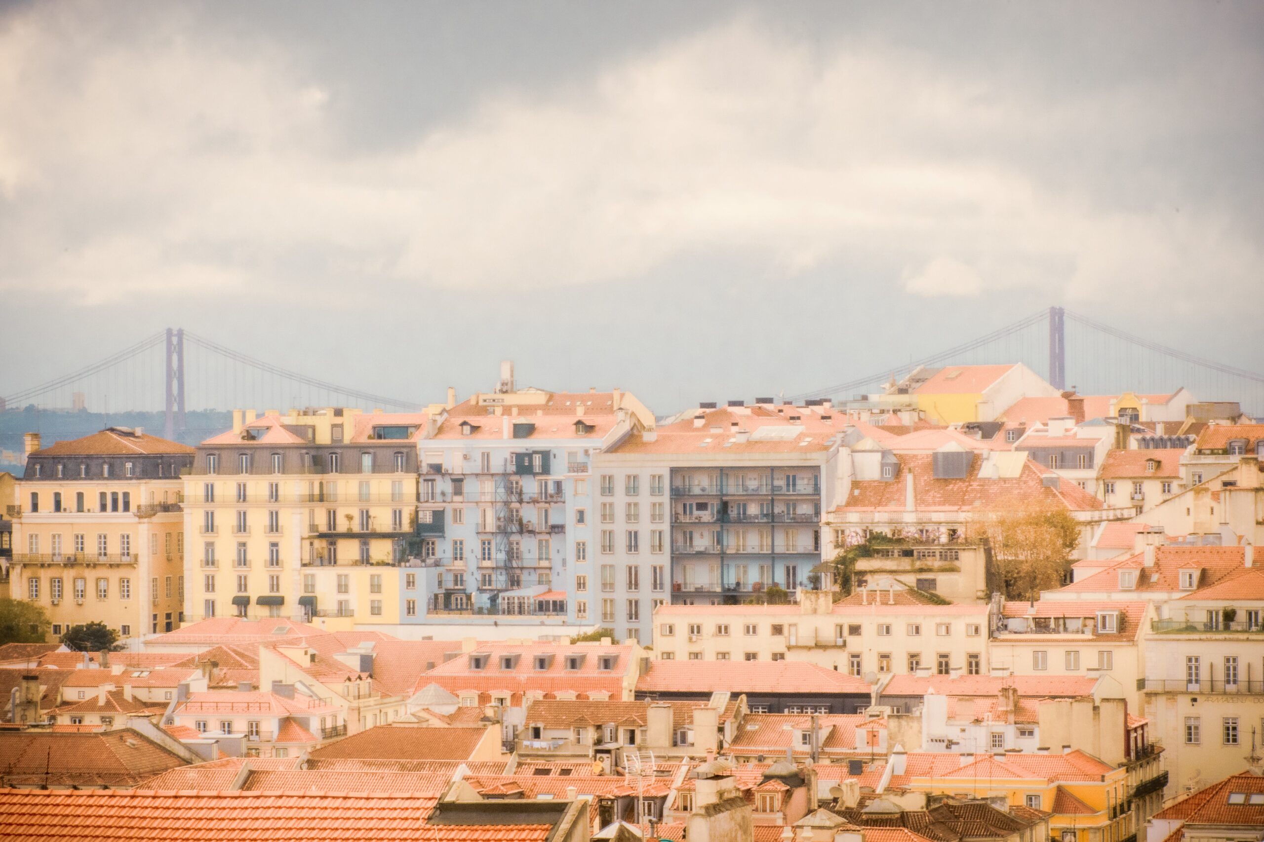 red rooftops with colourful buildings with bridge and sea in one day in lisbon