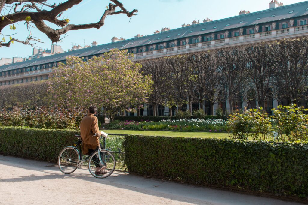 park with man alone in paris leaning on his bike
