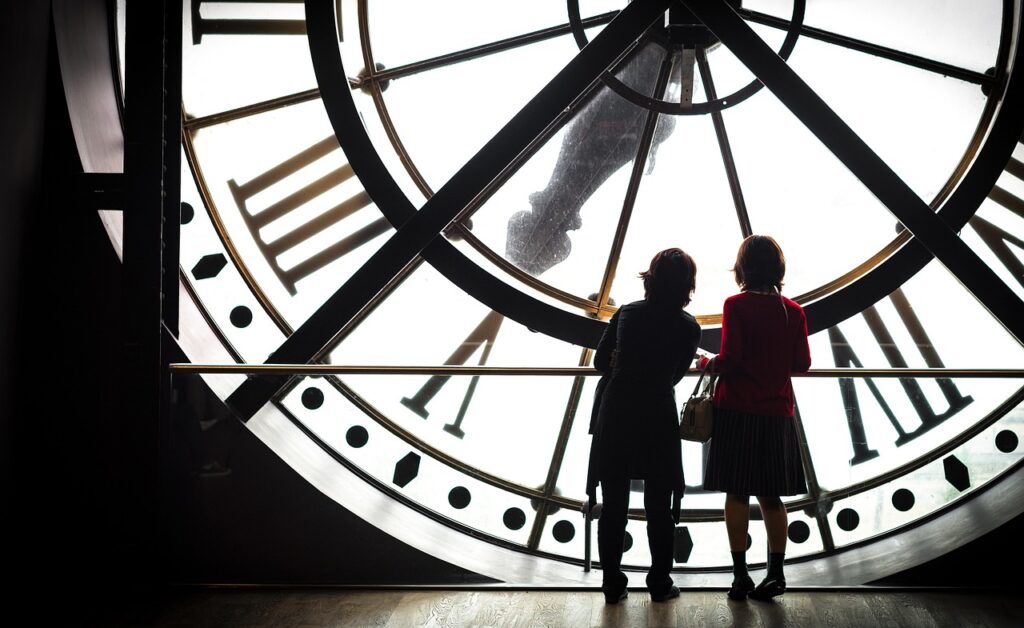 2 people standing in front of large clock on paris solo trip