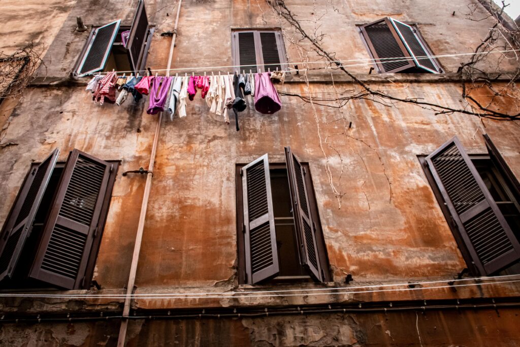 ochre colour building with shutters and laundry hanging in visit to rome