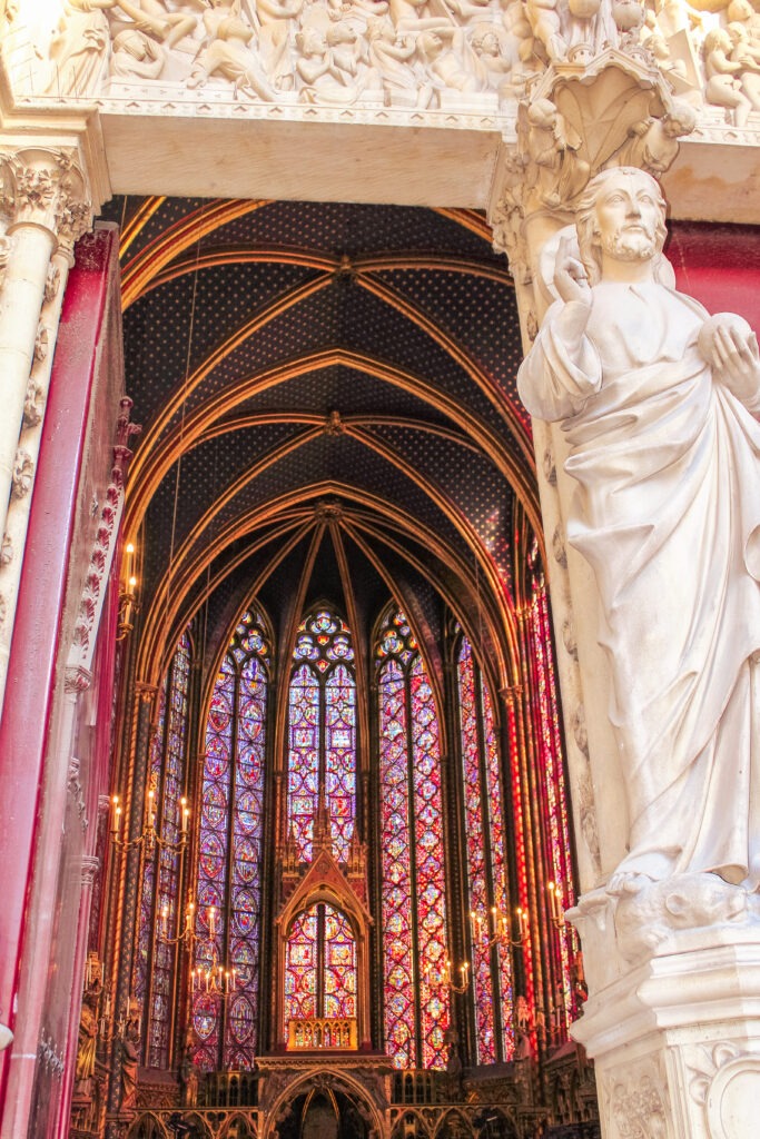 statue with stained glass windows in paris sainte chapelle 
