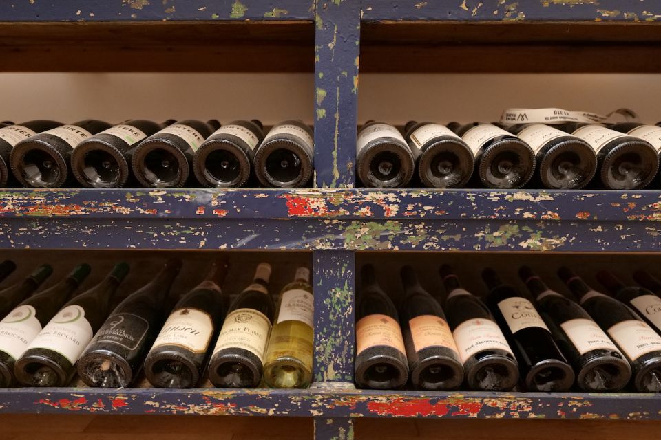 wine bottles lined up on a shelf during a paris wine tours