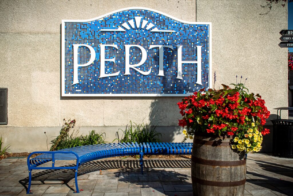 blue sign with wine barrel and flowers and blue bench in perth ontario