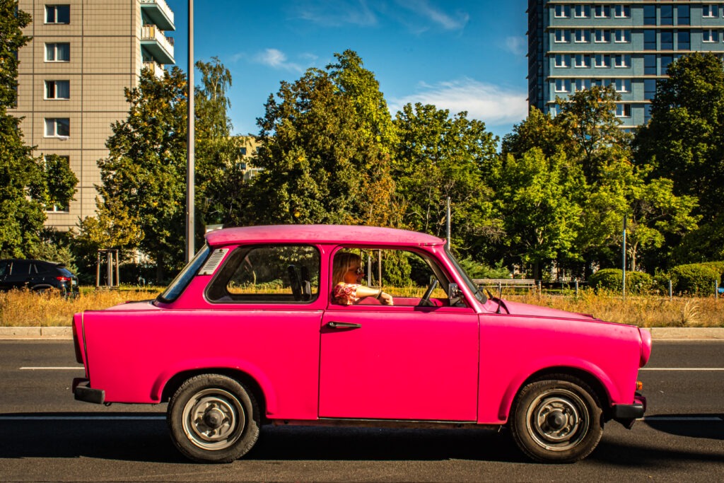 pink car on street showing the east berlin and west berlin differences in cars