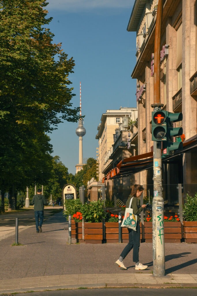 TV Tower, person walking at street sign when looking at east berlin and west berlin differences