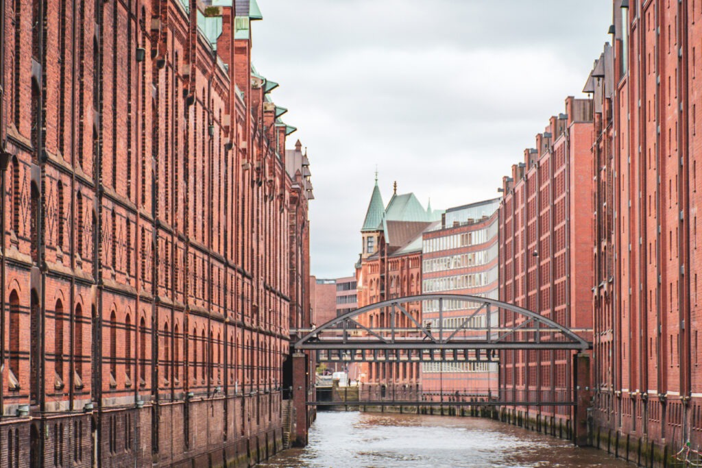 tall red brick buildings over canal with bridge on road trip in germany to hamburg