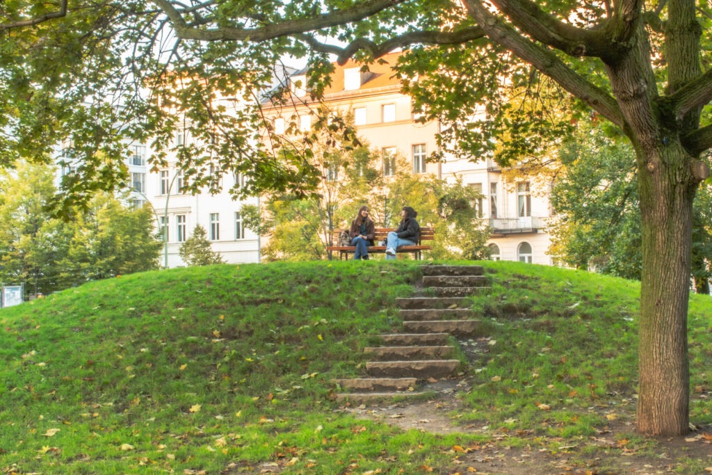 famous park in berlin with tree and bench with 2 girls talking
