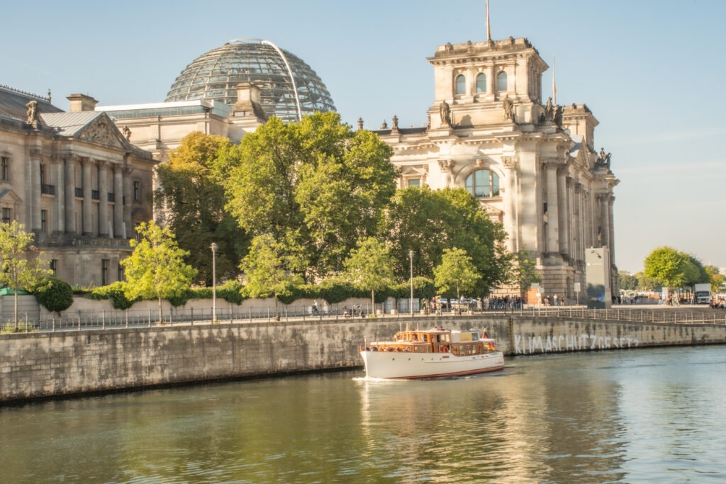 boat on river in berlin with buildings when comparing berlin vs paris
