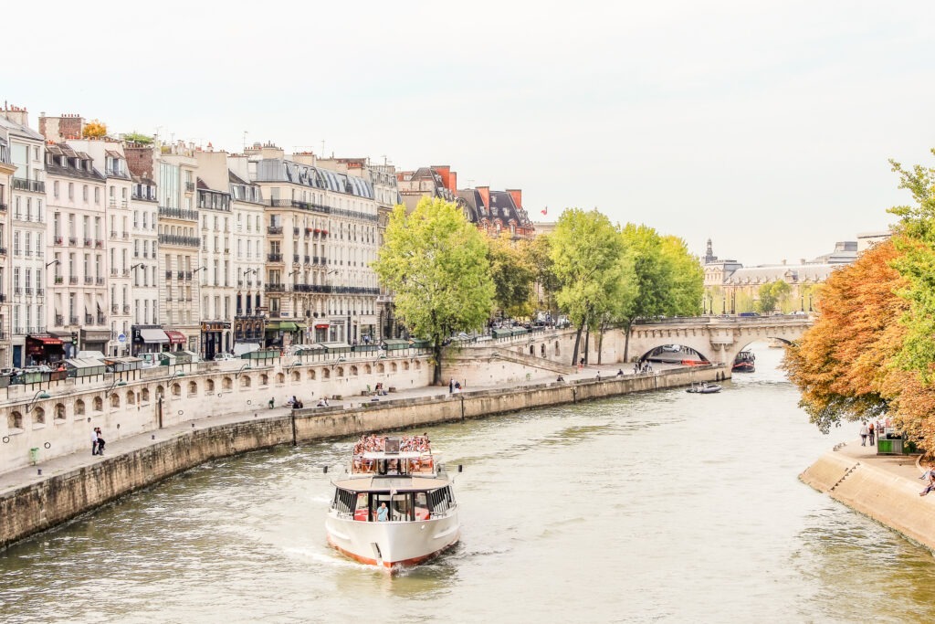 river with boat with townhomes when comparing paris or berlin