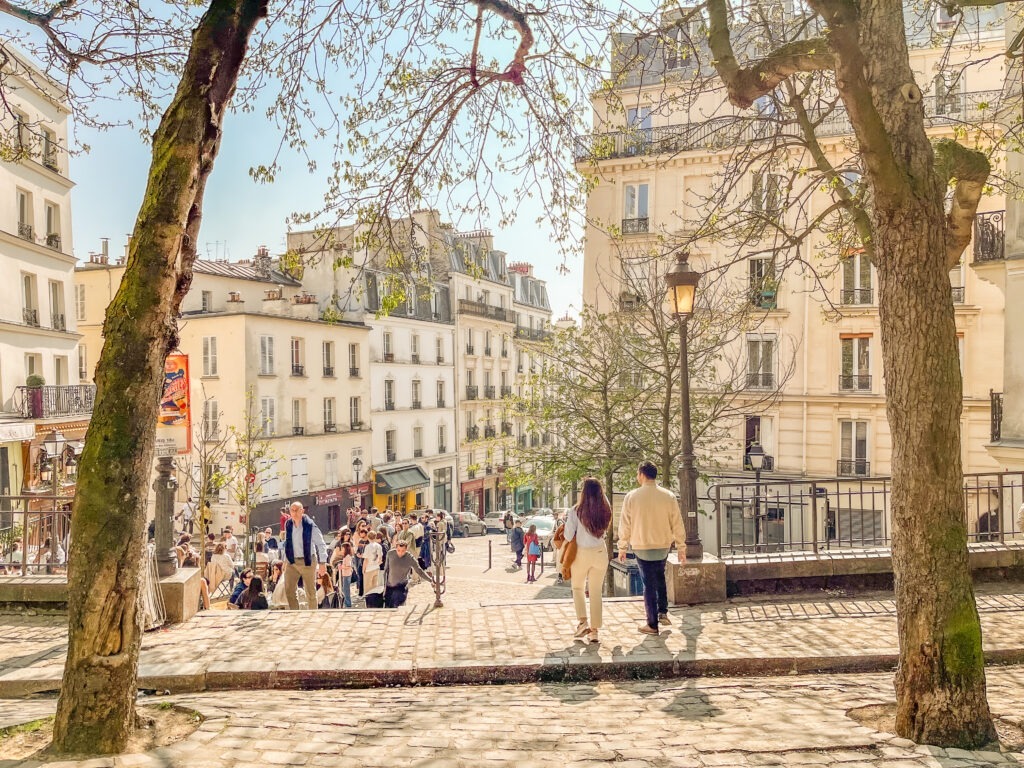 cobblestone street in paris with trees in springtime when looking at differences between paris and berlin
