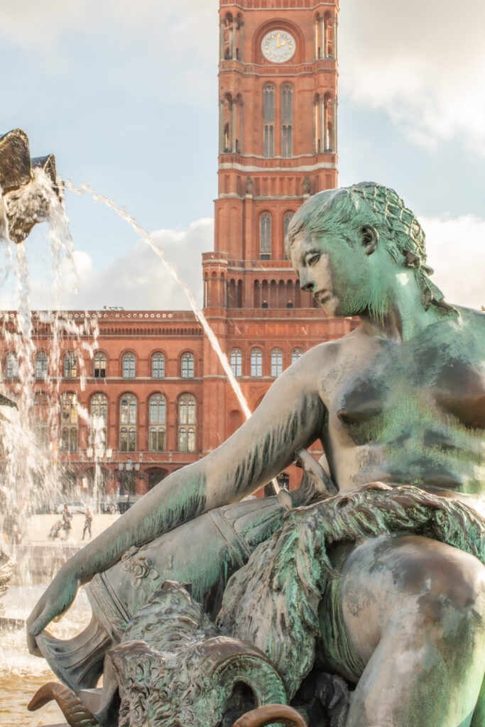 best views in berlin showing bronze statue of girl in water fountain and red city hall