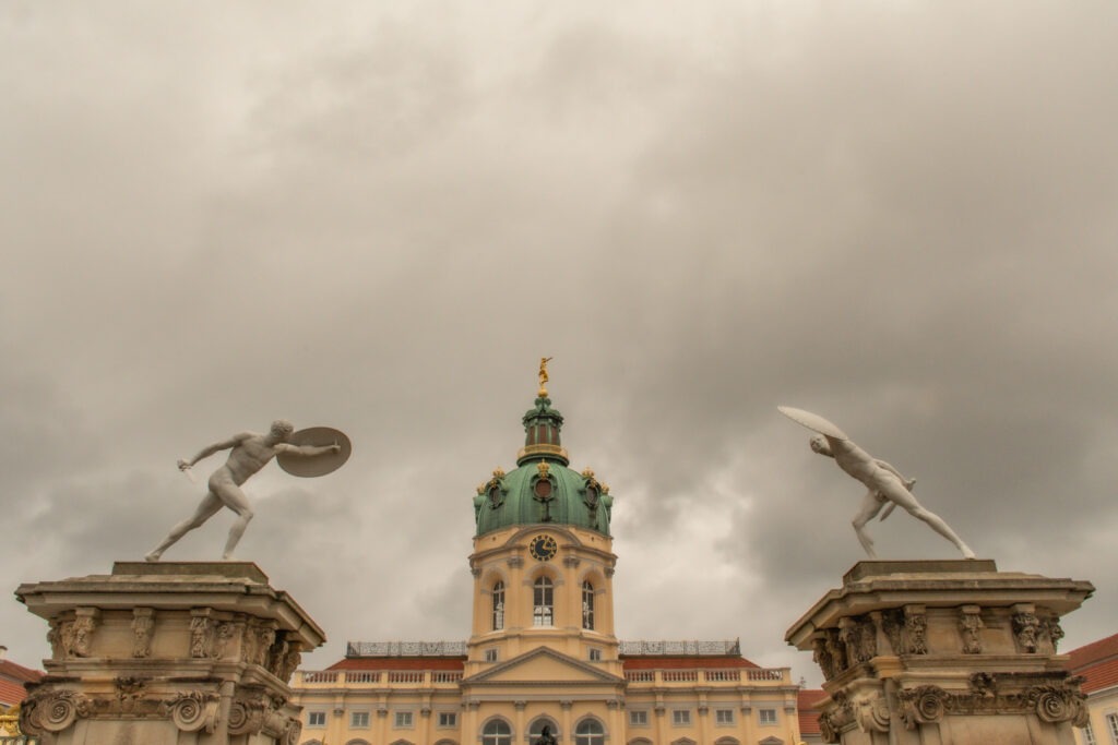 two white marble statues in front of charlottenburg castle