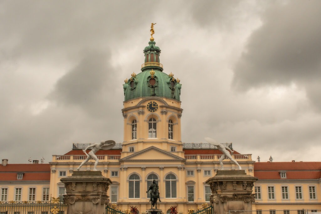 yellow castle with two white statues and dome in charlottenburg berlin