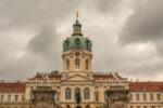 yellow castle with two white statues and dome in charlottenburg berlin