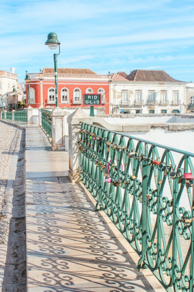 iron bridge with locks and colourful buildings as best things to do in Tavira Portugal