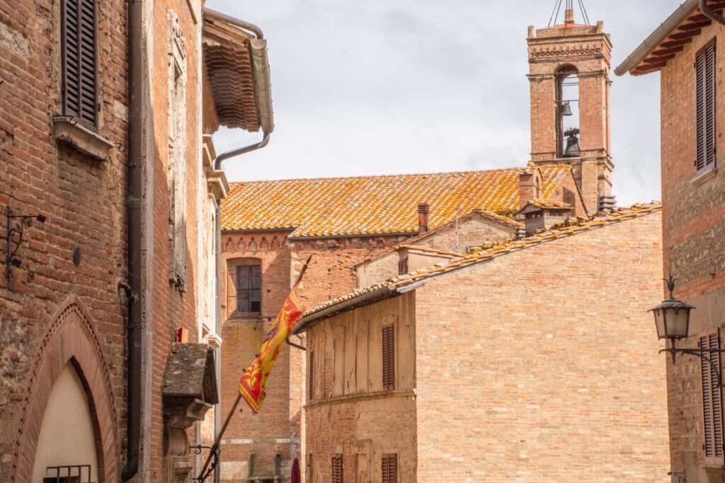 brown stone buildings with bell tower and flag in montepulciano tuscany italy