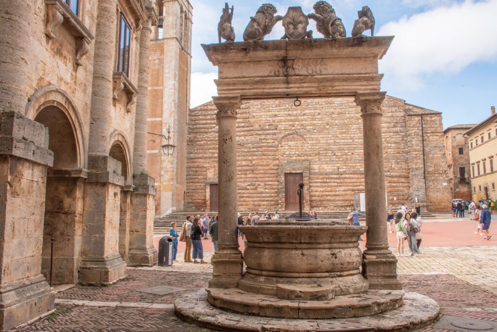 old well on town square with church in background is a must see in montepulciano