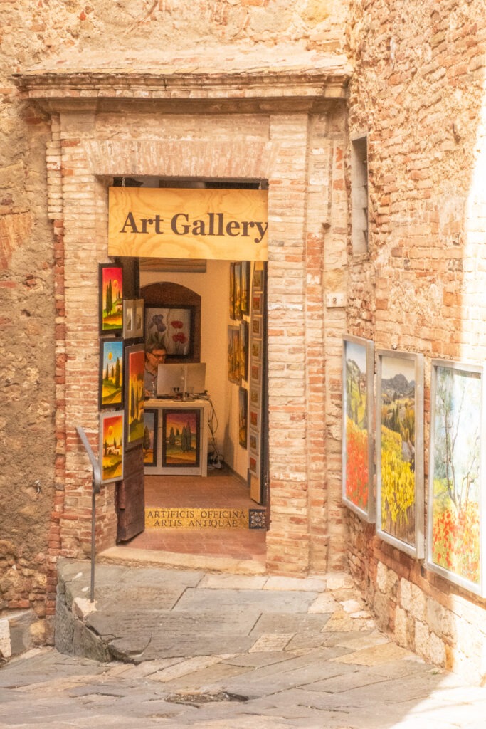 street with art on wall with open door to art gallery as things to do in montepulciano