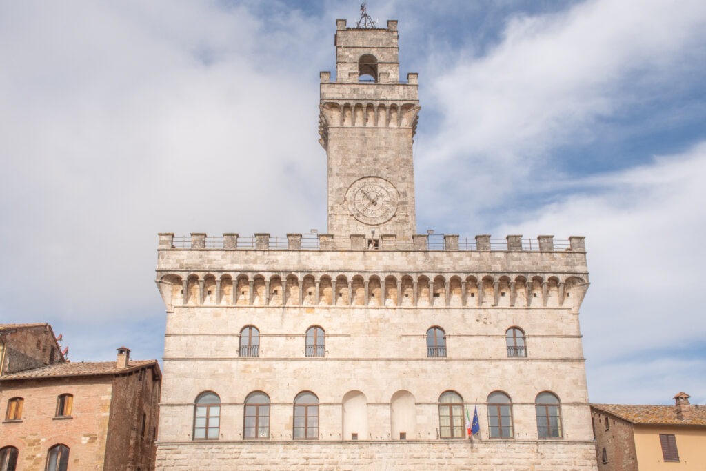 stone town hall with clock tower and blue sky is what to see in montepulciano