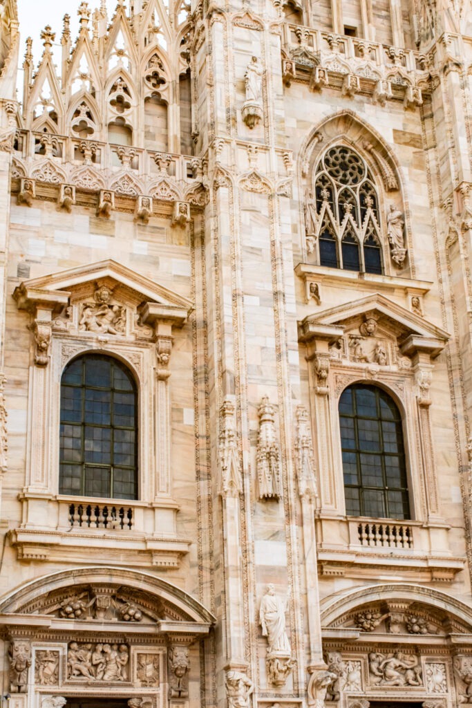 exterior of the milan duomo with elegant stone carvings and stained glass windows