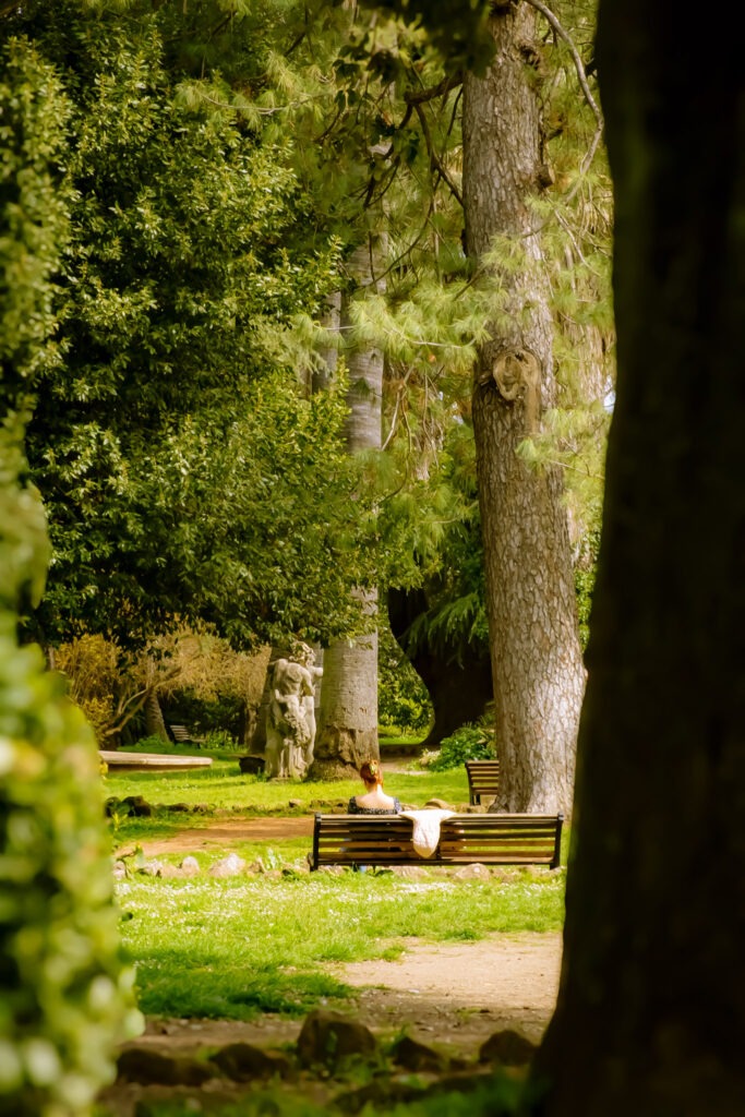 in a park with trees and a girl reading is an example of slow travel in italy