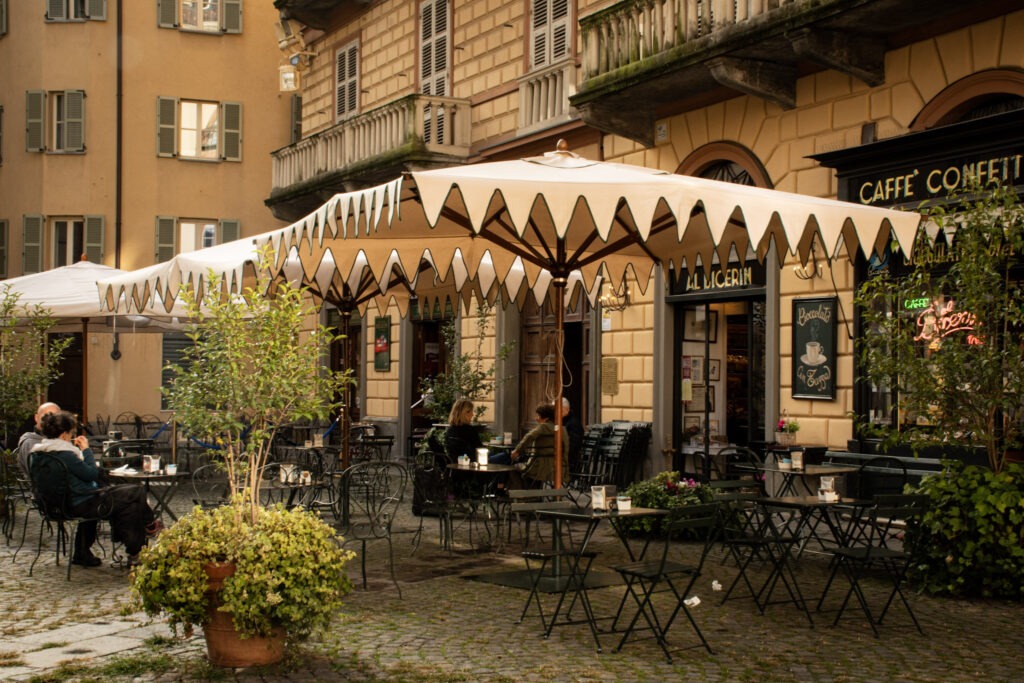 Turin is known for its cafe culture, showing tables and chairs, umbrellas in front of a cafe in turin