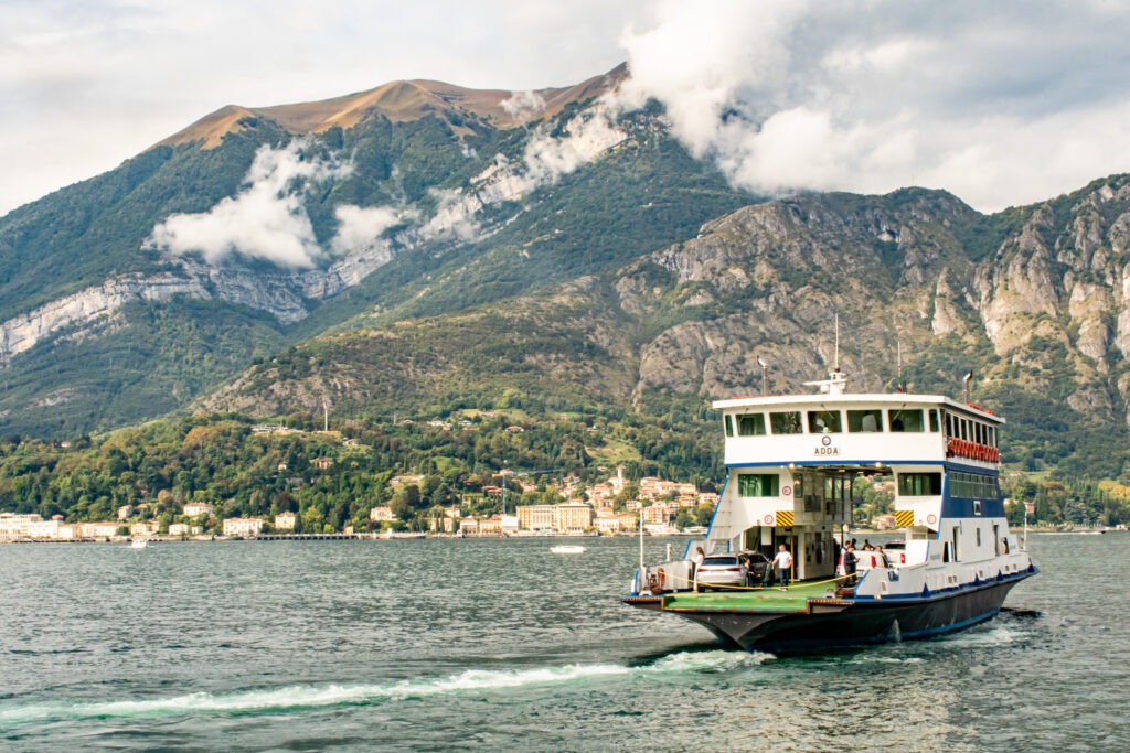 while on a day trip from milan to lake como, this is a ferry crossing lake como with mountains and clouds