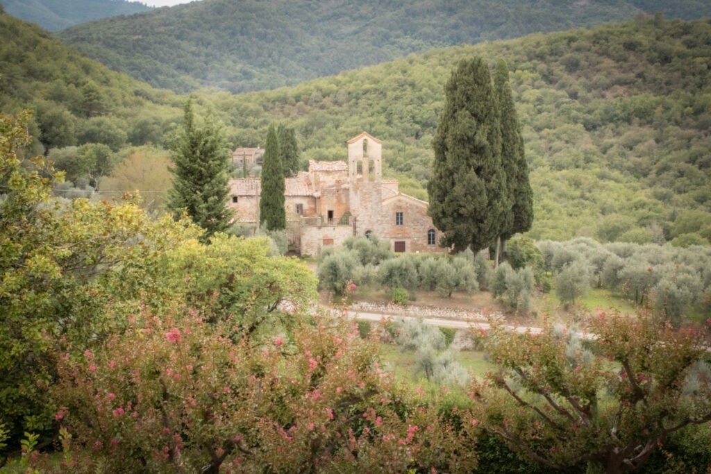 old church in tuscany with olive groves and green mountains