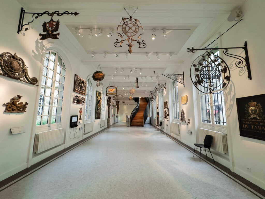 inside of paris museum showing long hallway with antique shop wrought iron signs 